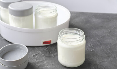Obraz na płótnie Canvas homemade yogurt making, glass jars with kefir. fermented dairy product made in yogurt making machine. probiotic food for gut health. good digestion concept. 