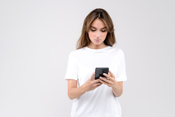 Fototapeta premium Cheerful businesswoman reading a text on mobile phone isolated on white background studio shoot