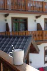 white mug with a hot drink on the balcony in front of a vintage wooden terrace. relax concept. vertical image