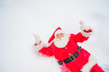 Happy santa claus lying in the snow and fooling around