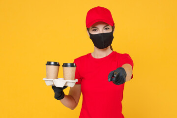 Delivery employee woman in red cap blank t-shirt uniform protect face mask gloves work courier service during quarantine coronavirus covid-19 virus hold coffee paper cups isolated on yellow background