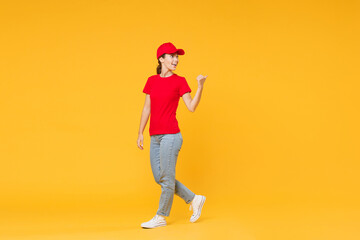Fototapeta na wymiar Full length body delivery employee woman in red cap blank t-shirt uniform work courier in service during quarantine coronavirus covid-19 virus standing isolated on yellow background studio portrait.