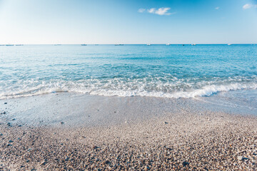 Pebble beach in Condofuri Calabria Italy with fishing boats on the horizon