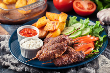 Grilled shish kebab served with fried potatoes