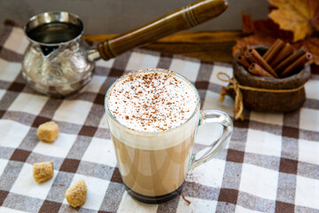 Pumpkin spice coffee with whipped cream and seasonal autumn decoration. Cinnamon sticks and decorative little pumpkins.