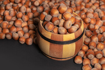 Filtered image of Hazelnuts in a wooden bowl on darck background