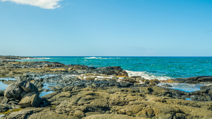 Fototapeta na wymiar Beautiful shore. Large boulder among the waves in the sea. Hawaii