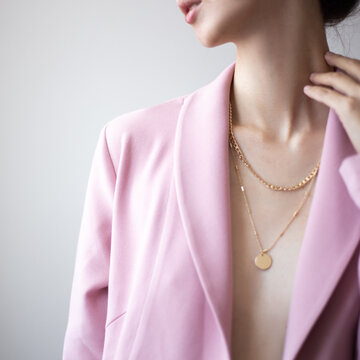 Closeup photo of young woman wearing pink jacket and golden necklace