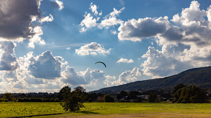 paraglider landing in rural area with clouds background