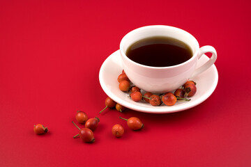 Rosehip tea in a white Cup on a red background. The concept of proper nutrition.