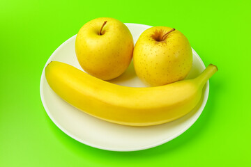 banana and Apple on a green background close-up. isolate