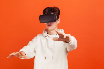 Young concentrated teenager in casual style hoodie discovering new technologies wearing virtual...