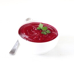 Beet soup-puree with croutons and parsley in a bowl on a white background