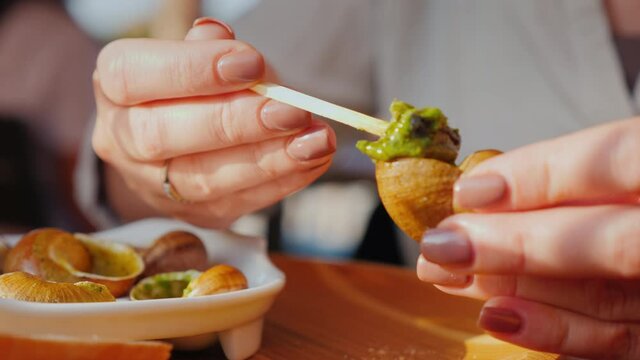 Closeup shot: Tourists taste snails - an exquisite dish of French cuisine