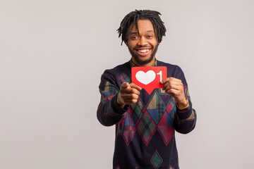 Extremely happy african male blogger holding in hand social media heart sign pointing at you, like...