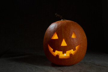Halloween pumpkin smile and scary eyes for party night. Close up view of scary Halloween pumpkin with eyes glowing inside at black background. Selective focus