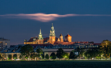 Obraz premium Wawel Castle and cloud illuminated by full moon, Krakow, Poland, seen from Blonia meadow.