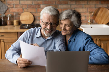 Happy elderly couple read postal paper document satisfied with banking health insurance contract or...