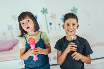 Family at home. Portrait of a happy children singing karaoke through microphone at home.