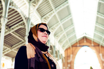 Obraz premium Muslim woman wearing headscarf and sunglasses inside a compound with a metal roof