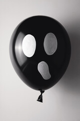 Black ball with a frightening face on a light gray background. Halloween scary decor concept