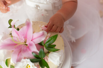 first cake. pink cake. the child takes the cake with his hand. hand in pastry cream. children's holiday
