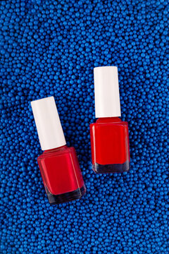 Two red nail polish on blue background of plastic texture balls. High quality photo
