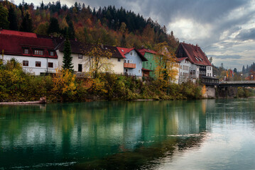 Wonderful landscape of mountain village in fall. View of forest with yellowed foliage, which reflects in water. Fussen. Lech river. Bavaria. Germany.