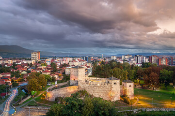 Beautiful night view of Pirot city in Serbia with ancient fortress in the foreground, dramatic sky and fireworks in the distance