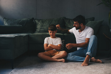 Father and son spend time together in the living room, sitting on the floor and talking about life