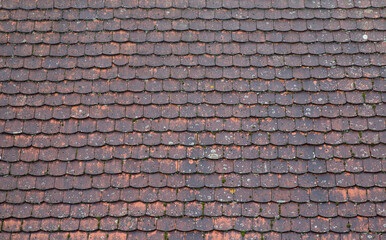 Tiled roof in Europe, Germany. Travel picturesque background and texture photo. Detailed view of wet old red roof shingles. Colorful photo