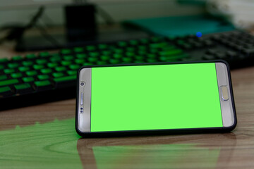 chroma key smartphone green screen placed on a computer desk background