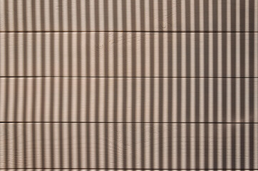 Wooden light brown background and vertical shadows on it.