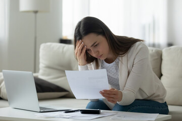 Unhappy young woman distressed by bad news bankruptcy notification in post letter correspondence....