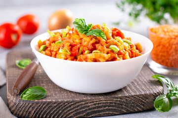 Healthy vegetable soup with red lentils, vegetables and greens in a white ceramic plate