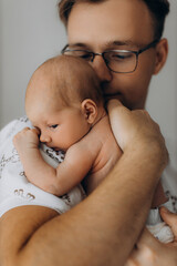 Handsome man hold adorable newborn baby girl in arms, caring dad look with love at the little daughter, enjoy tender parenting moments, fatherhood concept