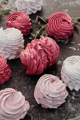 Multicolored natural marshmallows with berries and flowers on dark background.