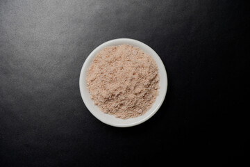 Himalyan rock salt in white bowl over black background, top view              