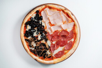 Italian pizza with salami, cheese, mushrooms and ham on a white plate. Four varieties of pizza in one.