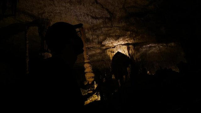 Man walking in low key overlooking cave's iluminated roof.
Mid angle, traveling movement, 4k 60p.