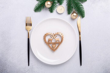 Christmas table setting with gold gifts and fir tree branch on stone background. Top view. Copy space