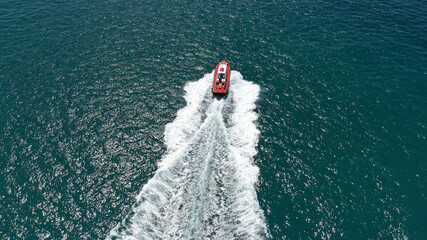 Aerial drone photo of red pilot boat cruising in high speed in Mediterranean deep blue sea offering navigational aid to ships