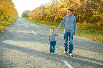Obraz premium A Happy parent with child are walking along the road in the park on nature travel