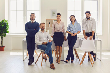 Group portrait of happy young businessmen and businesswomen after meeting in modern office - obrazy, fototapety, plakaty