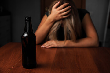 DRUNK WOMAN SITS NEXT TO A BOTTLE