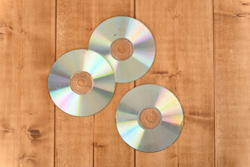 Old scratched worn out cd on the wooden table, top view.