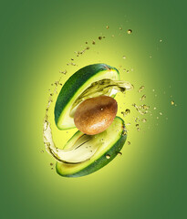 Sliced avocado with splashes of juice close-up on a green background