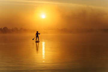 Young man in silhouette swimming on sup board