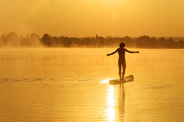 Healthy and fit man keeping balance on paddle board
