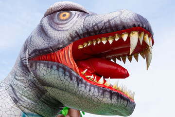 Inflatable dinosaur head on a child's playground against the background of the sky